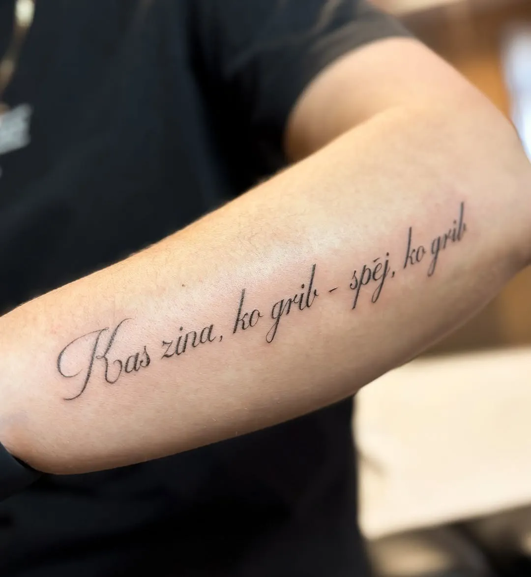 Kaligrāfisks uzraksts „Kas zina, ko grib – spēj, ko grib” uz rokas
